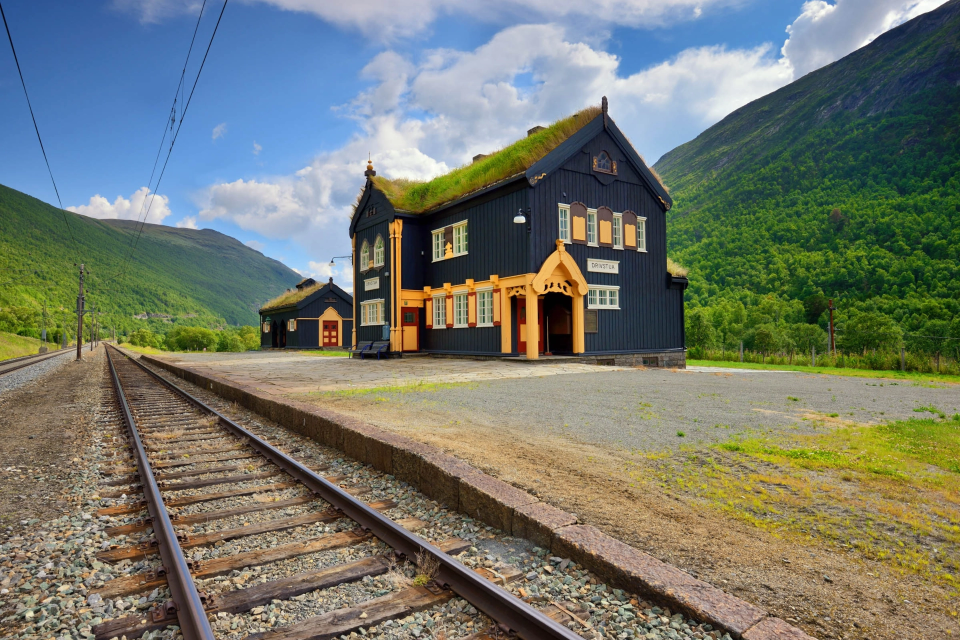 Toget kører forbi smukke, ældre stations-bygninger