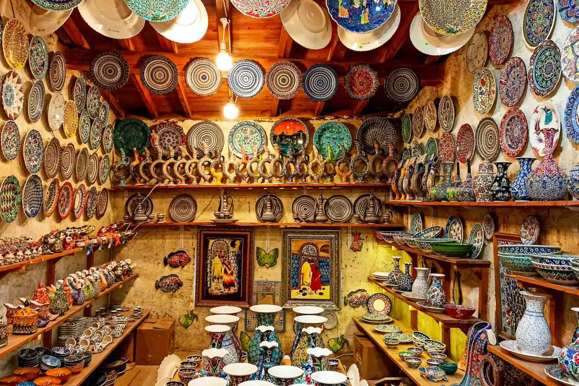 Butik med farverige, håndmalede keramikplader, skåle og vaser i en hyggelig, rustik atmosfære