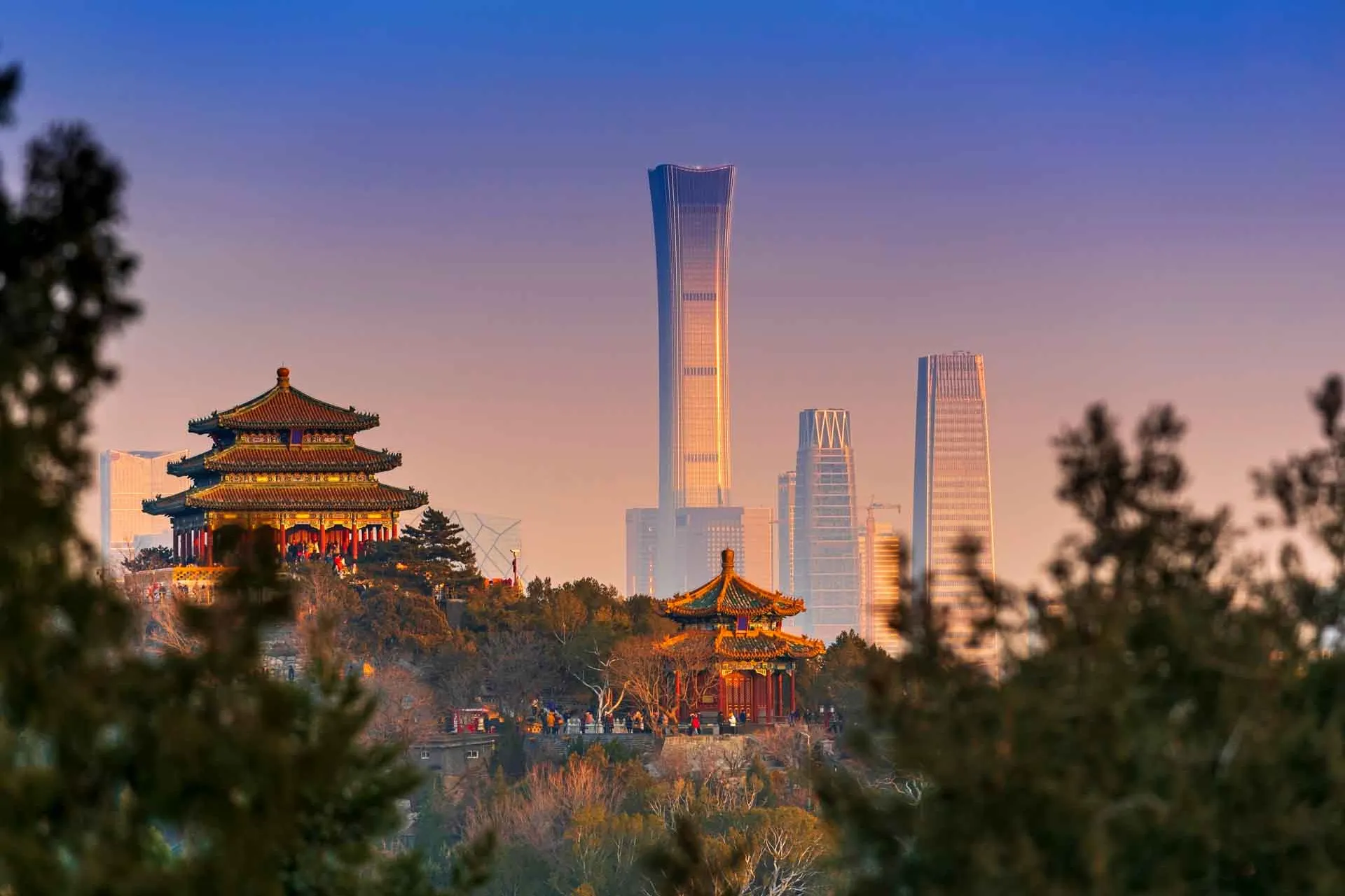 Solnedgang i Beijing med gammelt tempel og moderne skyskrabere