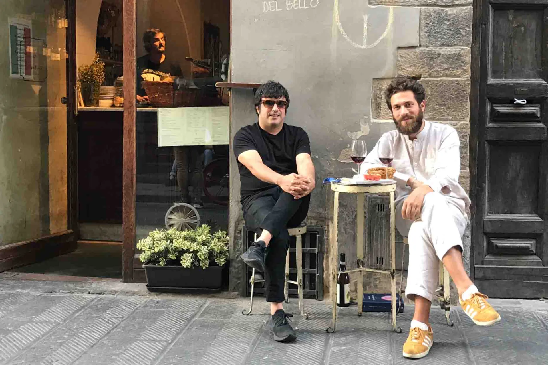 To mænd nyder et glas vin ved et lille bord på gaden