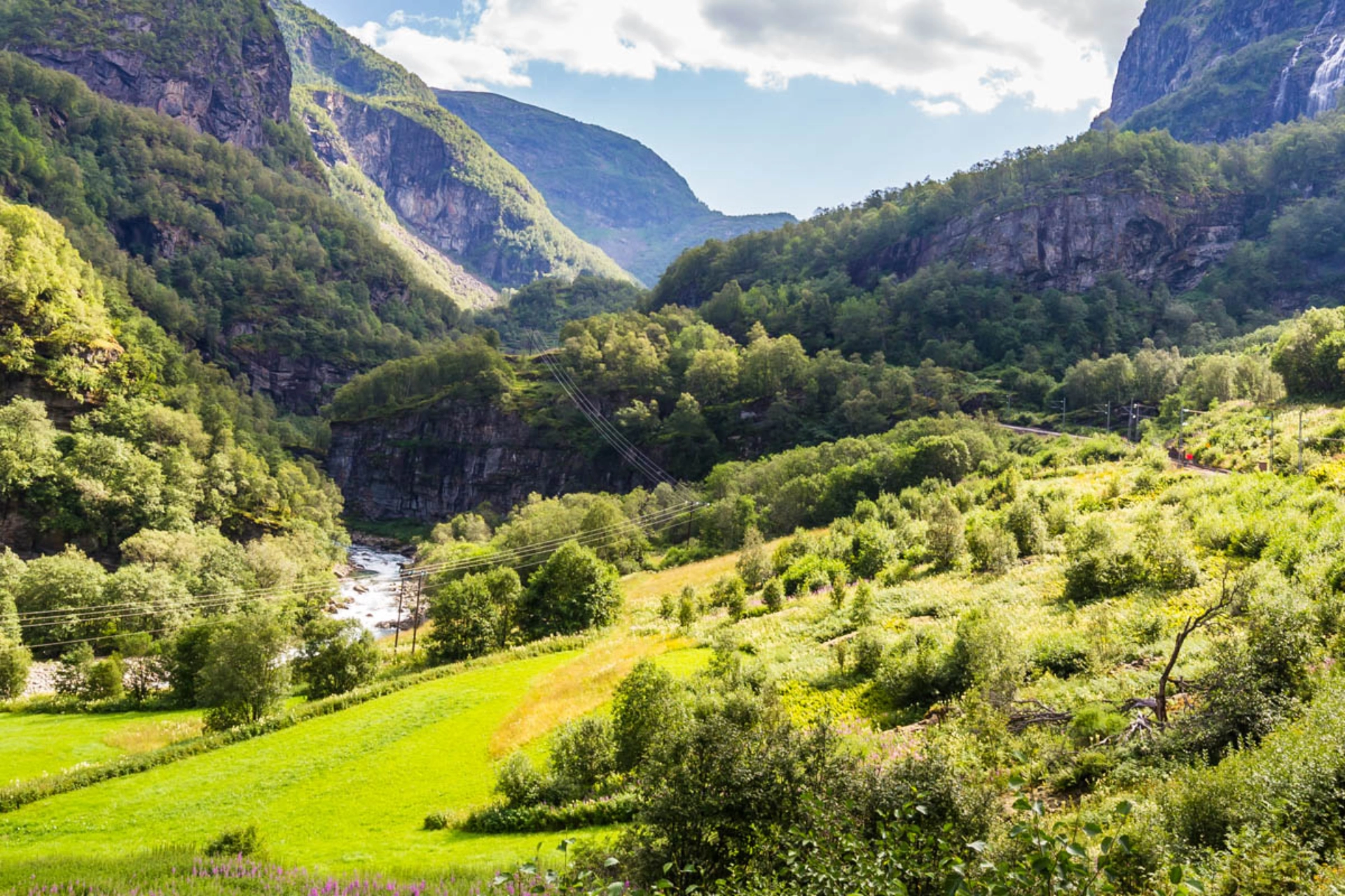 Toget kører langs brusende elve, fjelde og frodige dale