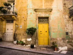 Charmerende facade med gul dør i Vittoriosa – et eksempel på Maltas farverige bymiljø Charmerende facade med gul dør i Vittoriosa – et eksempel på Maltas farverige bymiljø