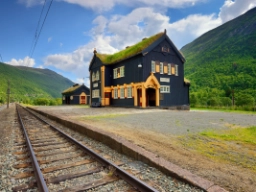 Toget kører forbi smukke, ældre stations-bygninger