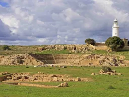 Odeon-teatret i Paphos Arkæologiske Park med det karakteristiske fyrtårn i baggrunden