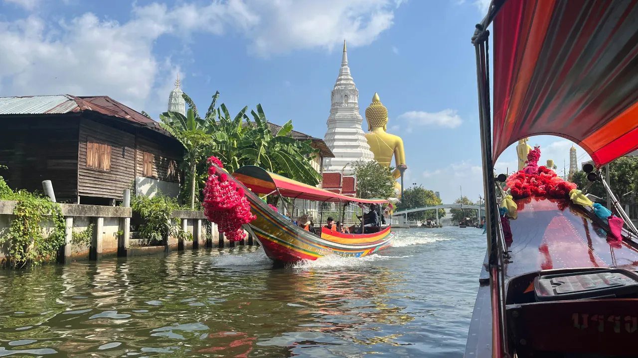Kanaltur i Bangkok med stor gylden Buddha-statue og en hvid chedi (stupa) i baggrunden