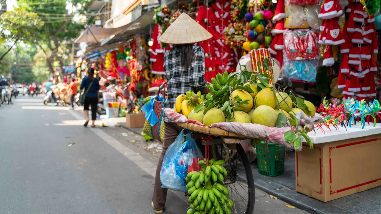 Frugtsælger med cykelbod på en livlig gade i Hanoi Frugtsælger med cykelbod på en livlig gade i Hanoi
