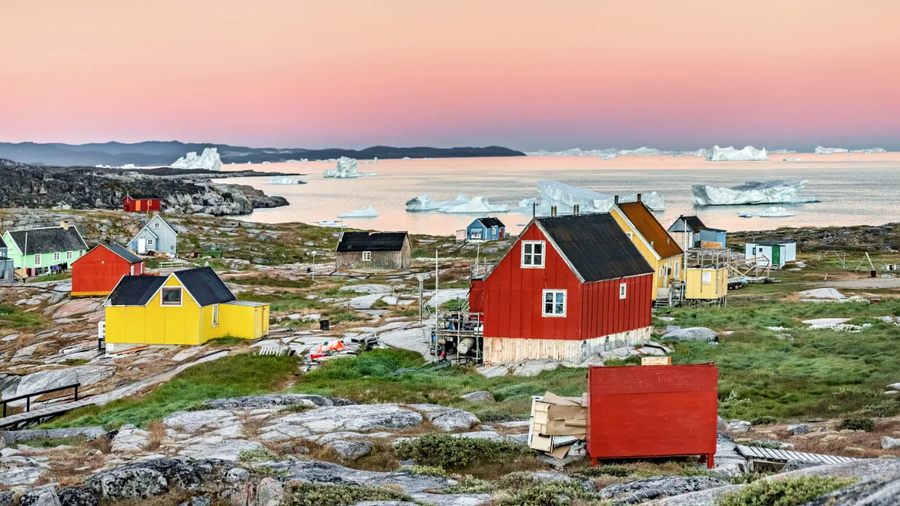 Oqaatsut i Vestgrønland badet i det bløde morgenlys med isbjerge i horisonten Oqaatsut i Vestgrønland badet i det bløde morgenlys med isbjerge i horisonten