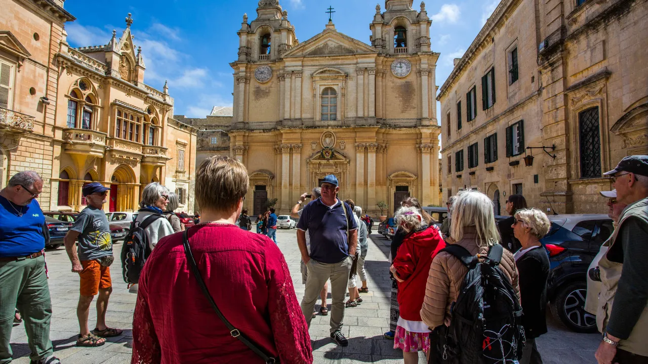 Guiden på arbejde i Mdina, Maltas gamle hovedstad, foran den imponerende Skt. Pauls Katedral Guiden på arbejde i Mdina, Maltas gamle hovedstad, foran den imponerende Skt. Pauls Katedral