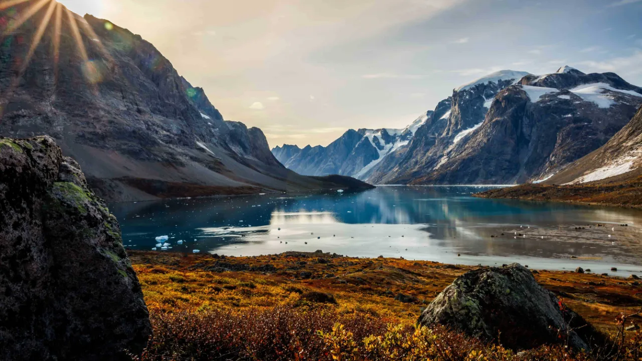 Sol over fjordlandskab i Sydøstgrønland
