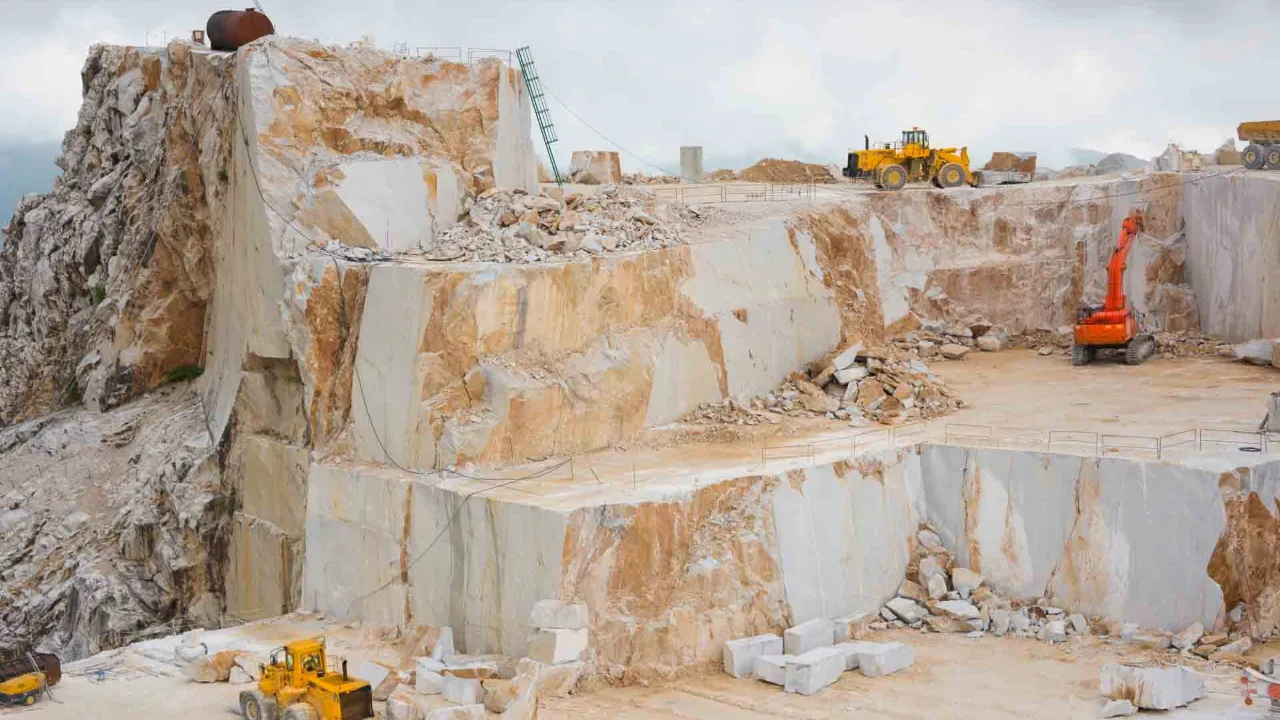 Carrara-marmorbrud med store stenblokke og arbejdsmaskiner Carrara-marmorbrud med store stenblokke og arbejdsmaskiner